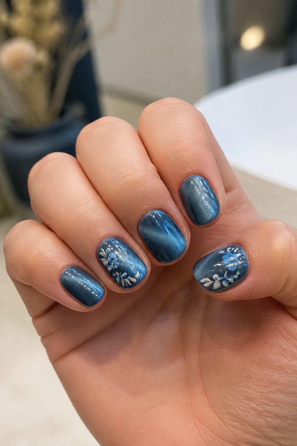 Short round nails in blue with a floral design and a cat eye finish, fall nail design