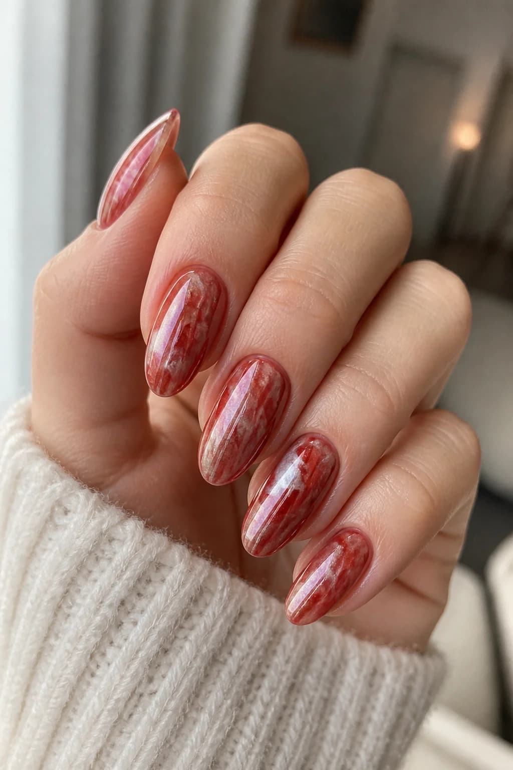 Medium almond nails in red with a marble design and a chrome finish