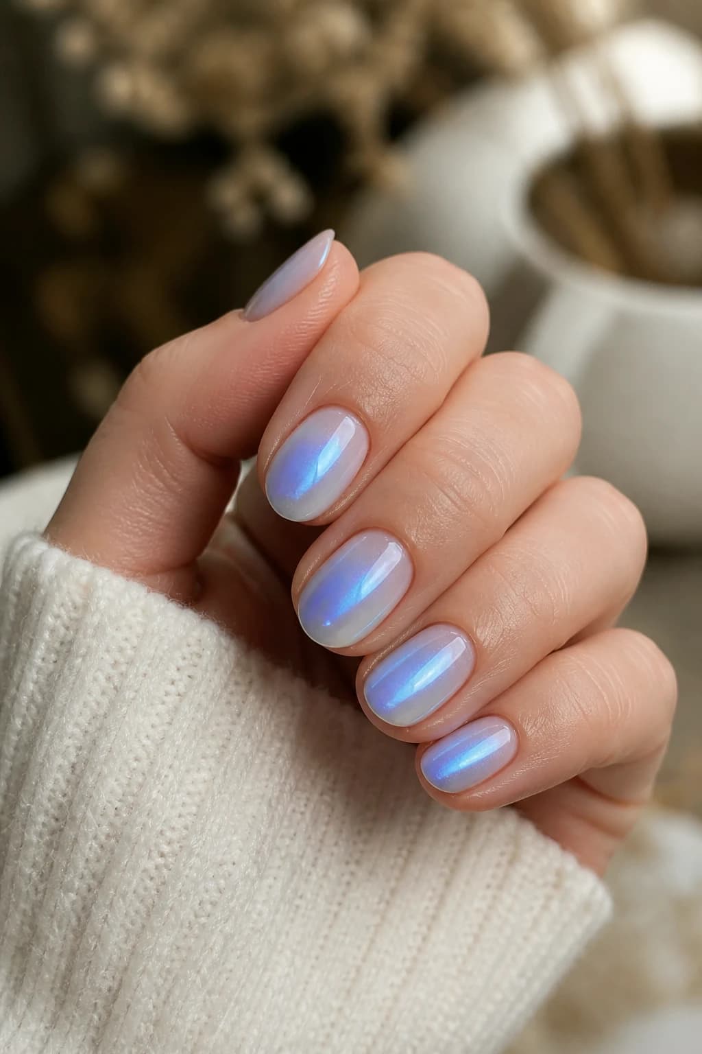 Short almond nails in blue with an aura design and a chrome finish