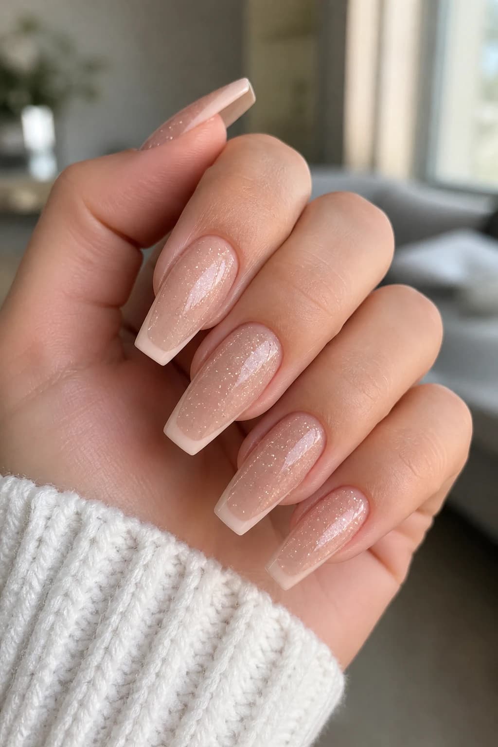 Medium coffin nails in nude with a French tip design and a glitter finish