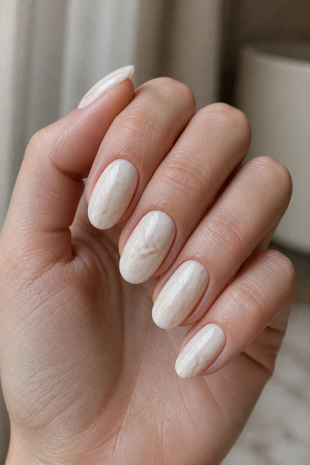 Medium oval nails in white and cream with a marble design and a glossy finish