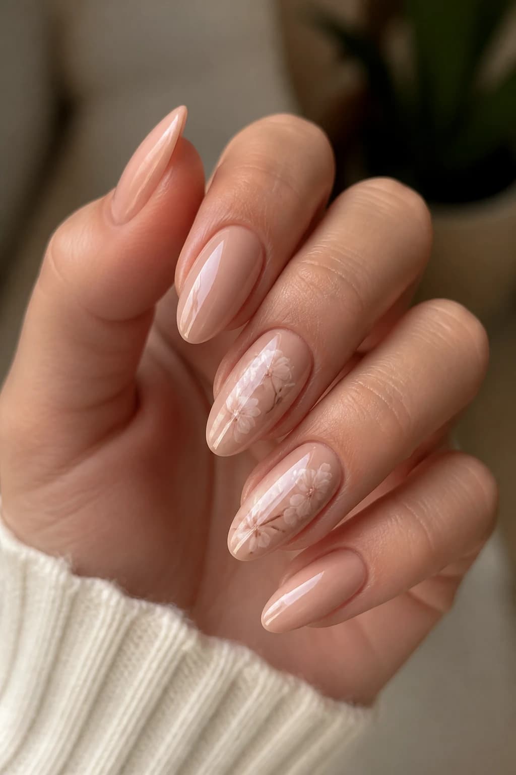 Long almond nails in nude with a floral design and a chrome finish