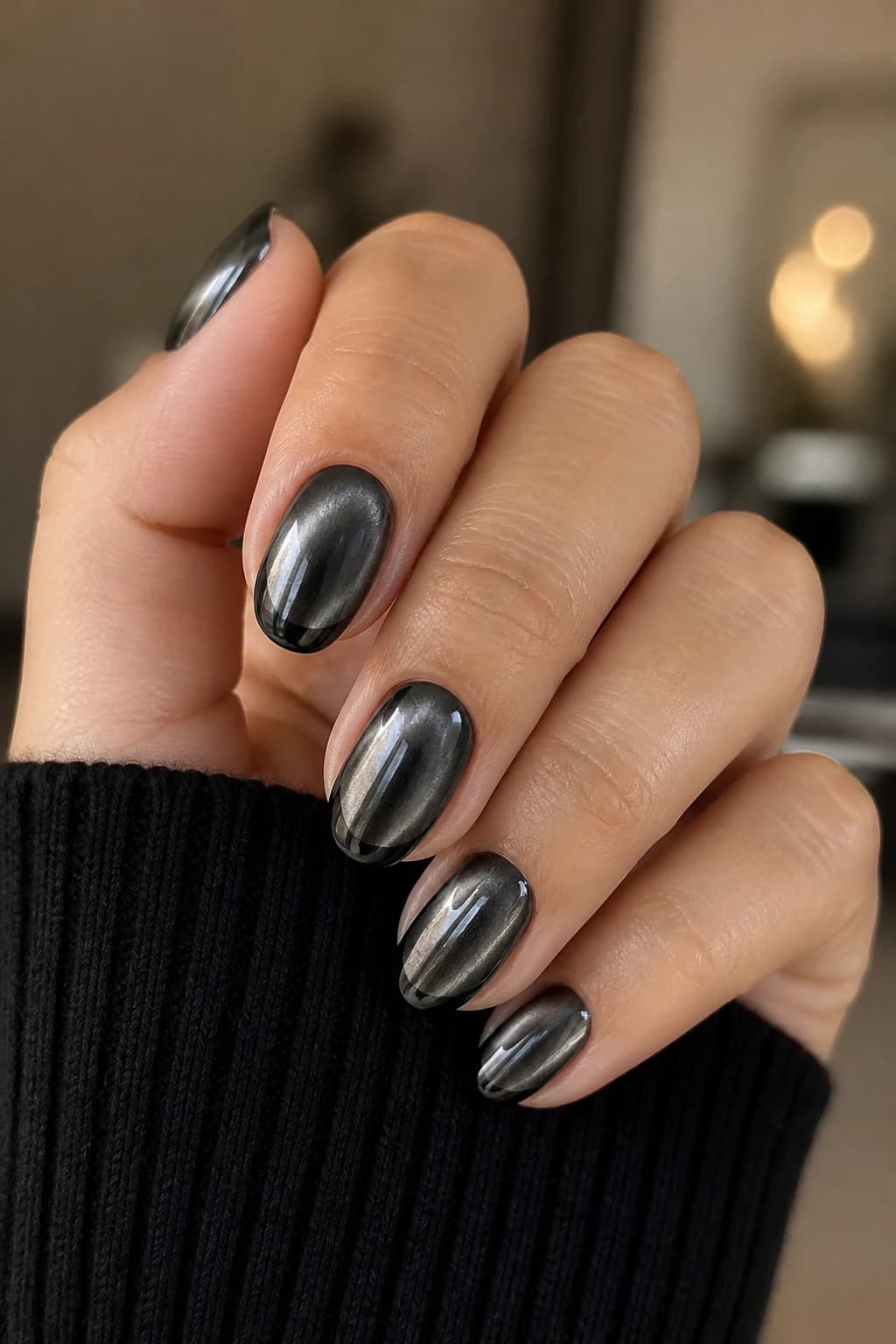 Short almond nails in black with a French tip design and a chrome finish