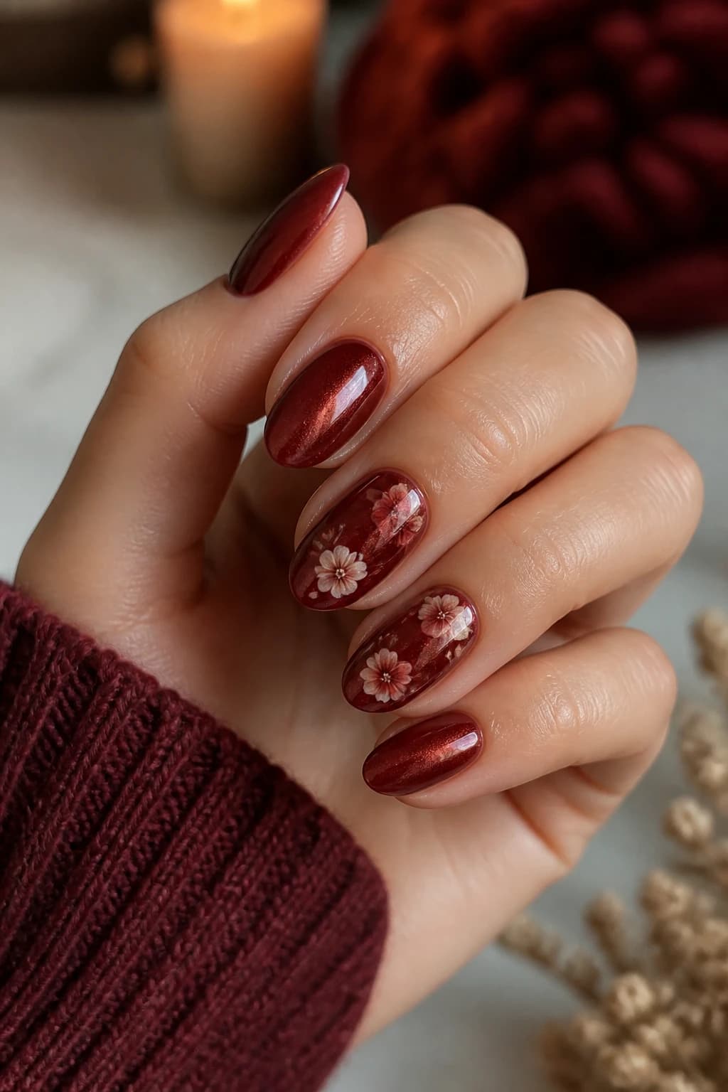 Medium oval nails in red with a floral design and a cat eye finish, fall nail design
