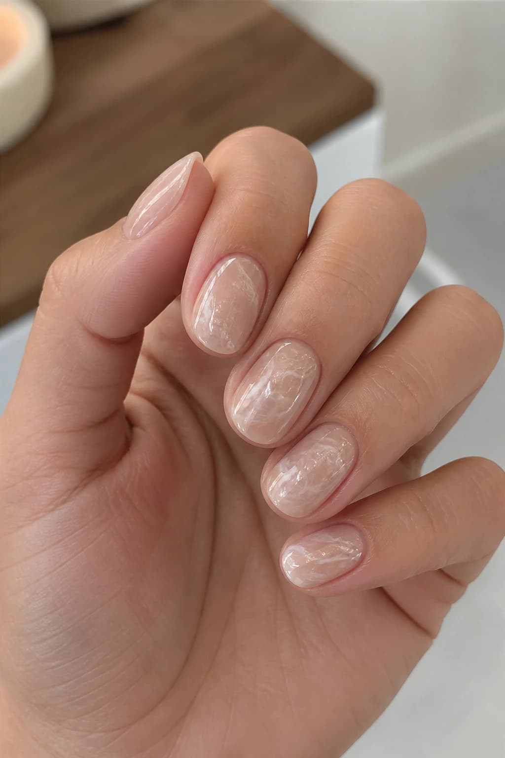 Short round nails in nude with a marble design and a chrome finish