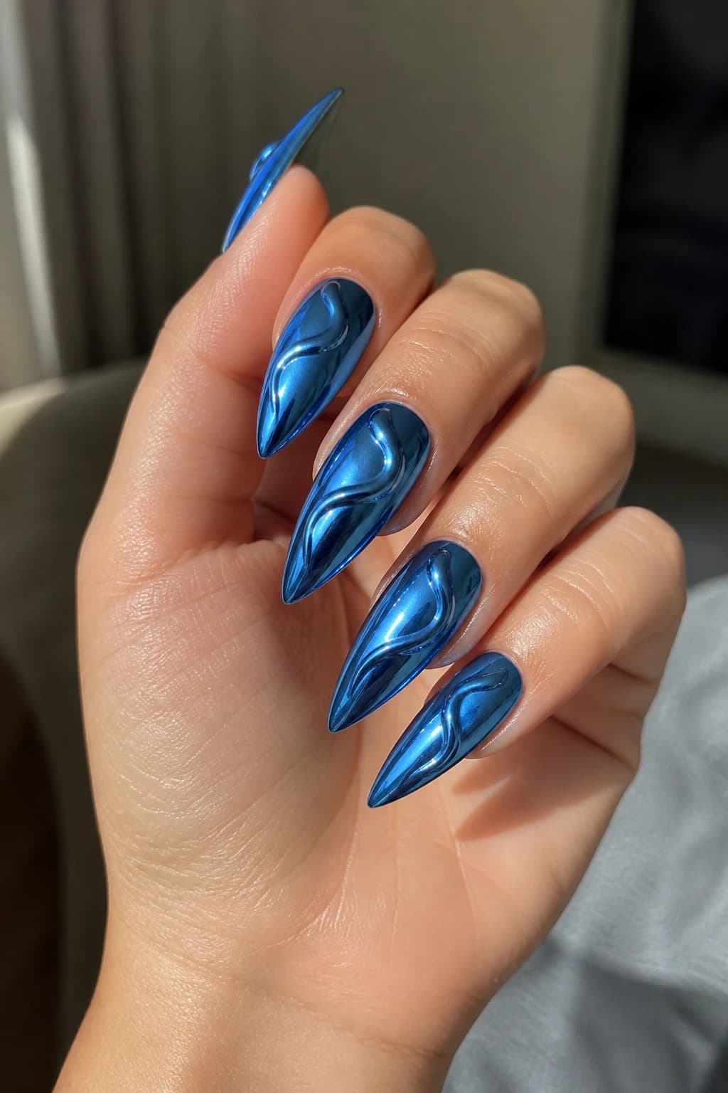 Long stiletto nails in blue with a 3D design and a chrome finish