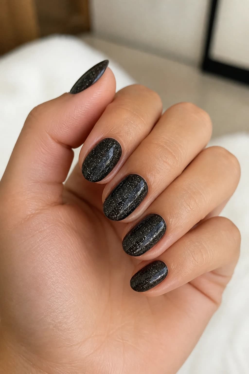 Short almond nails in black with a jelly design and a glitter finish
