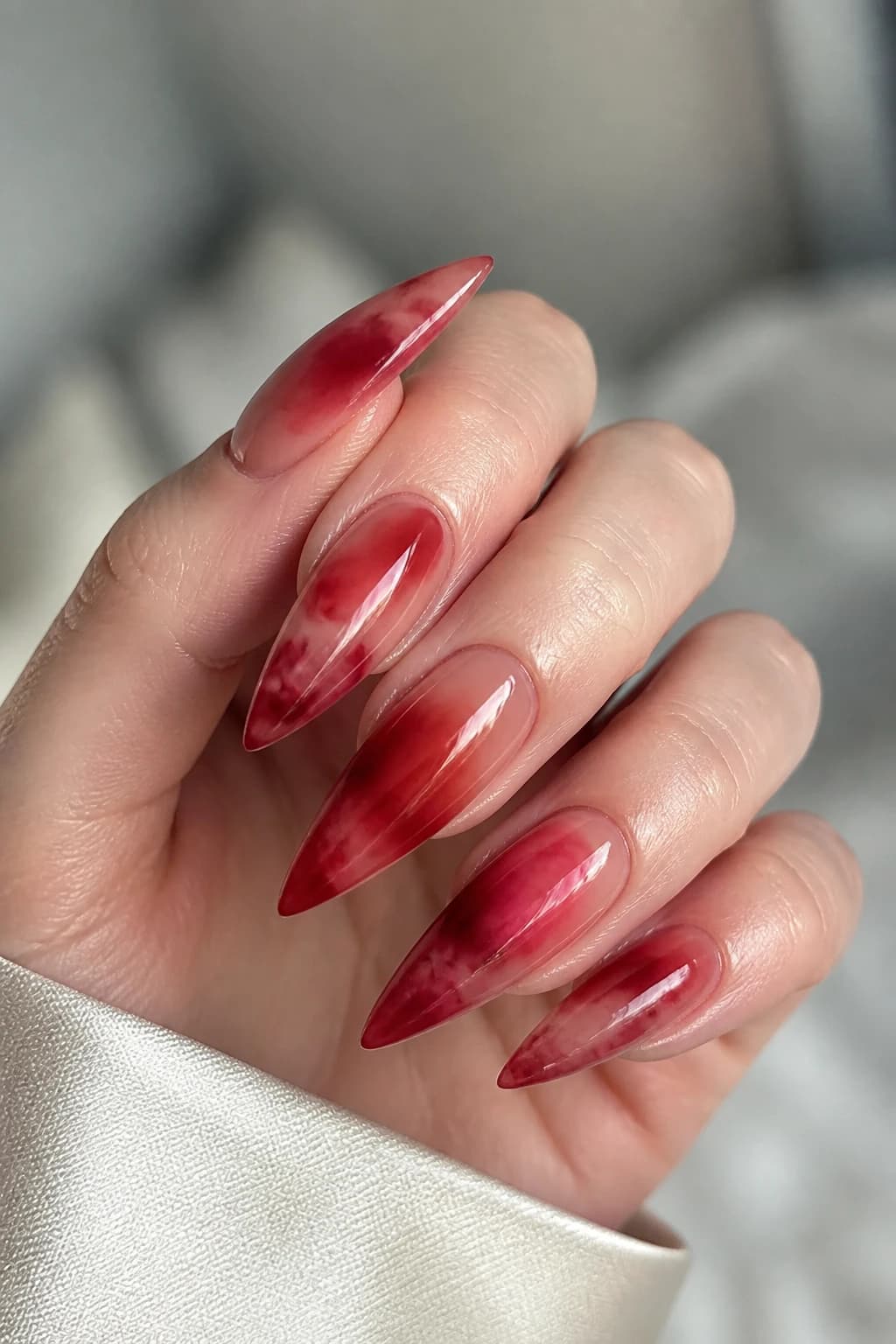 Long stiletto nails in red with a blooming gel design and a glossy finish