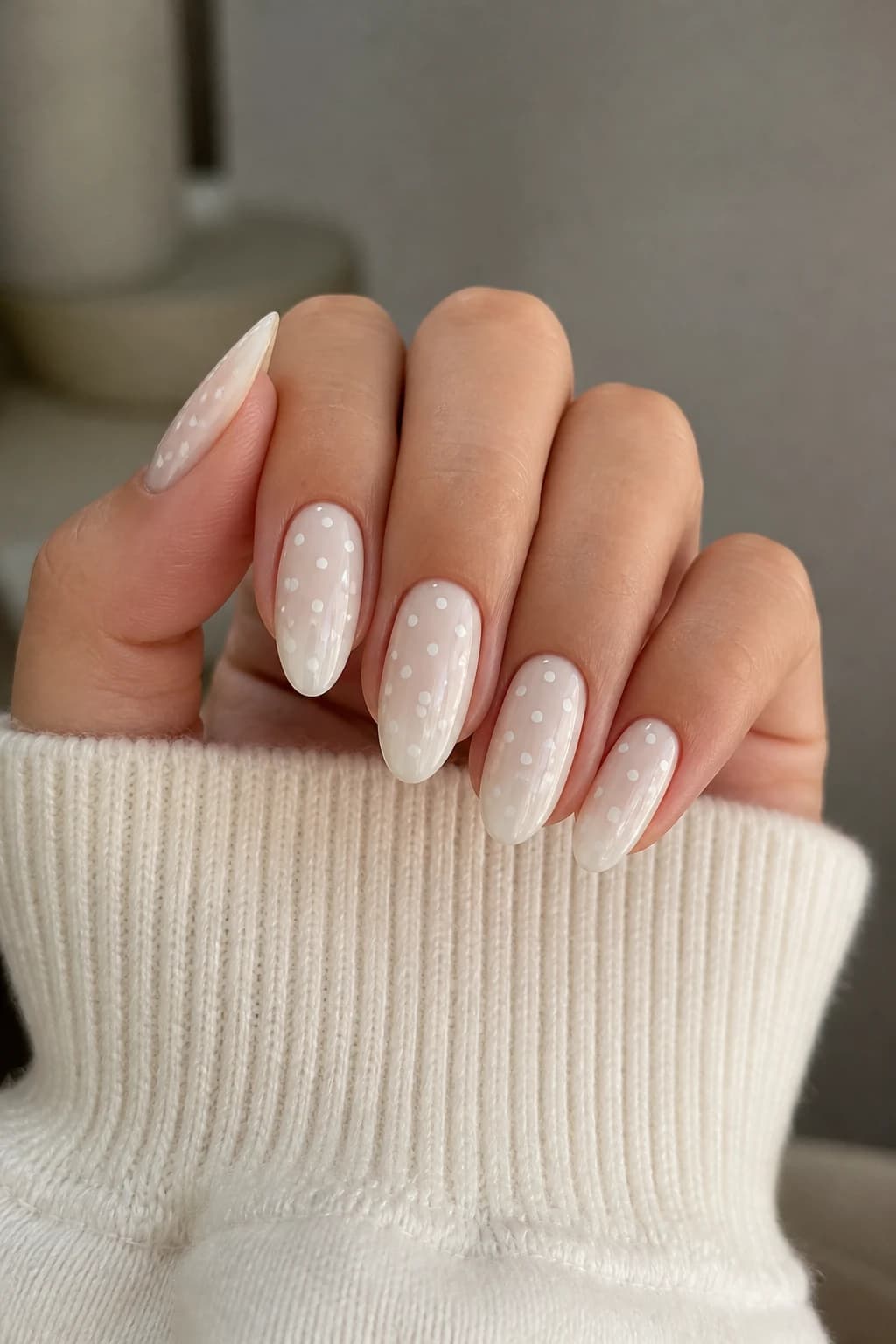 Medium almond nails in white and cream with a polka dot design and a glossy finish